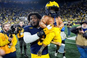 Michigan edge Josaiah Stewart celebrates with the Paul Bunyan Trophy.