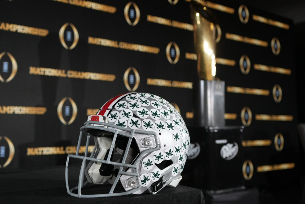 Ohio State football helmet next to the CFP trophy.