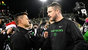 Dan Lanning and Bob Chesney shake hands.